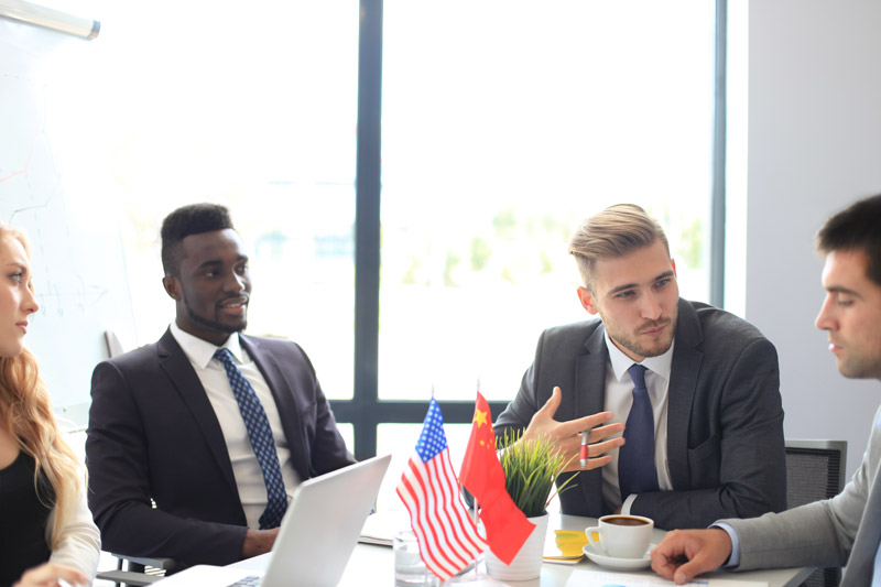 diverse group of young professionals around a table with country flags in the center